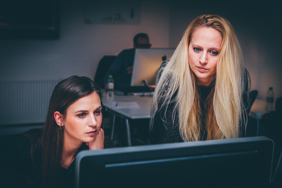 Two women look intently at a computer screen