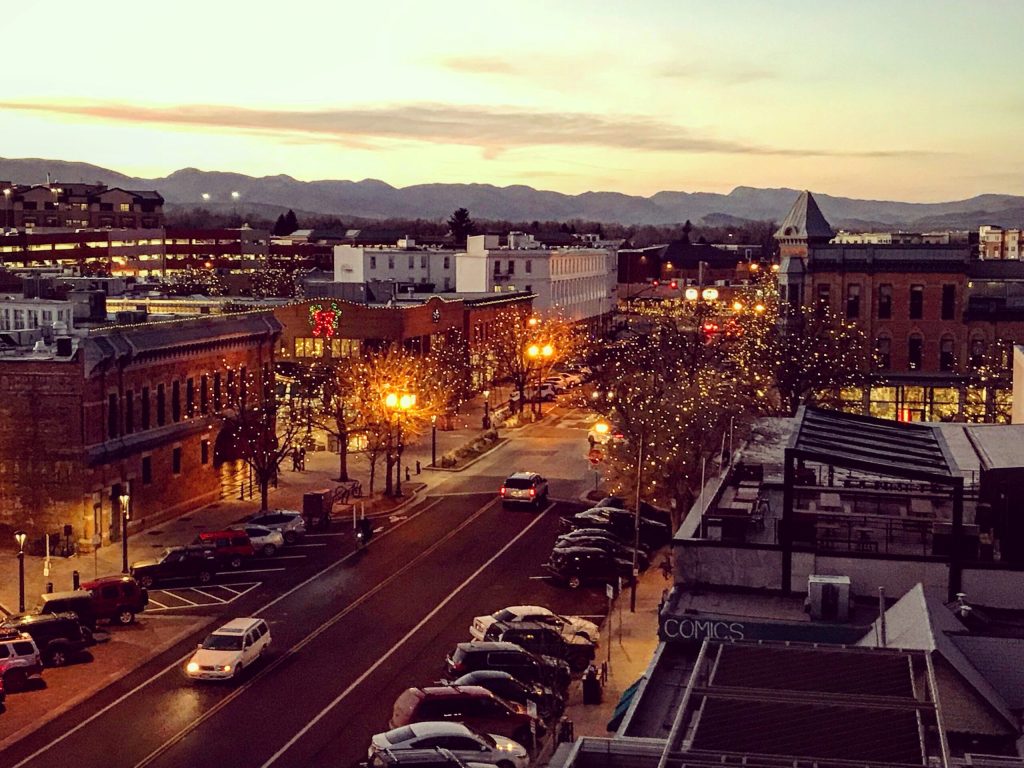 Old Town Fort Collins at sunset, seen from a rooftop lounge, with the foothills behind