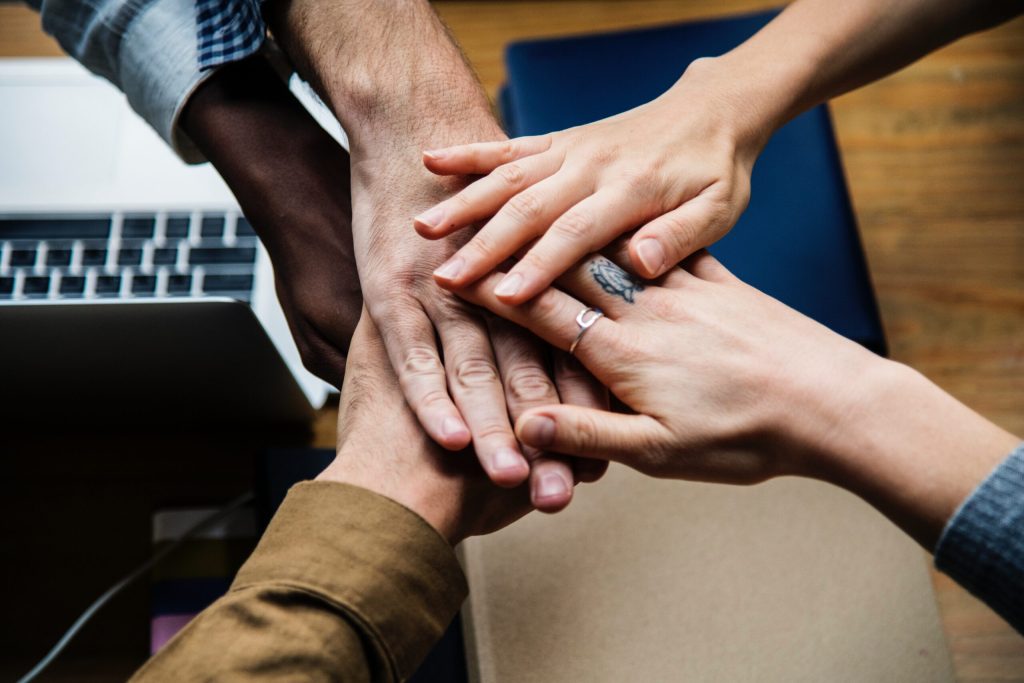A team stacks hands together over a desk