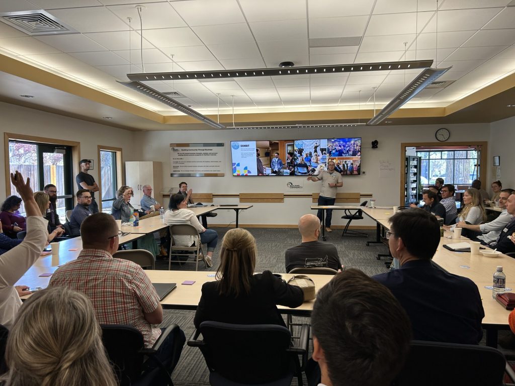 A full meeting room at the Founded in FoCo open house, with one attendee raising a hand