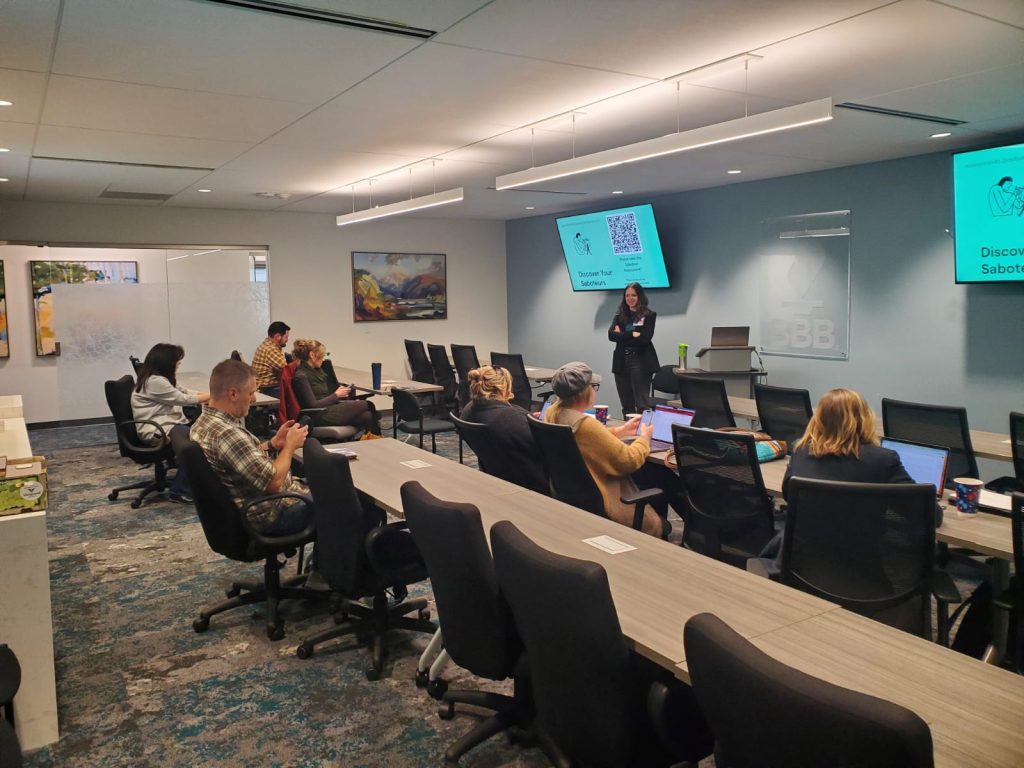 Attendees with laptops at a long conference table watch a presenter at Founded in FoCo 2024